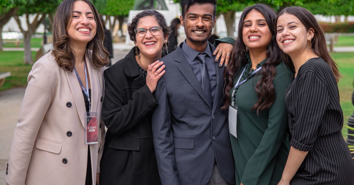 A group of diverse colleagues smiling together, showcasing teamwork and friendship outdoors.